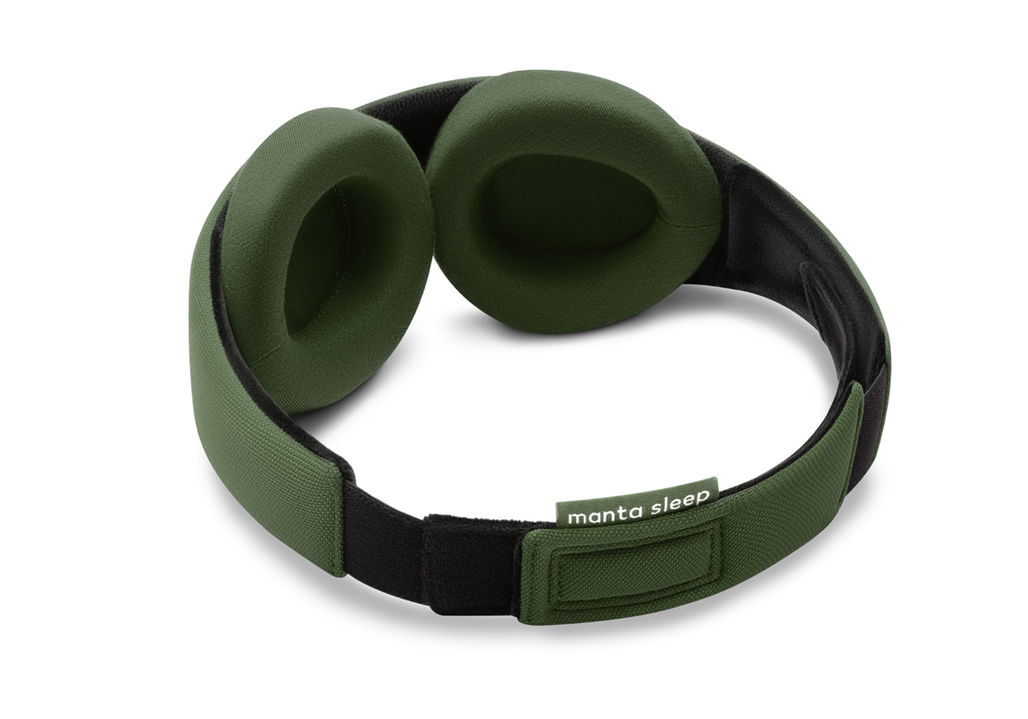 A three-quarter rear perspective of the forest green Manta Sleep Mask isolated on a white background. This view highlights the thick, cushioned green eyecups, the black inner plush lining, the adjustable green fabric rear closure, and the small brand label reading "manta sleep".
