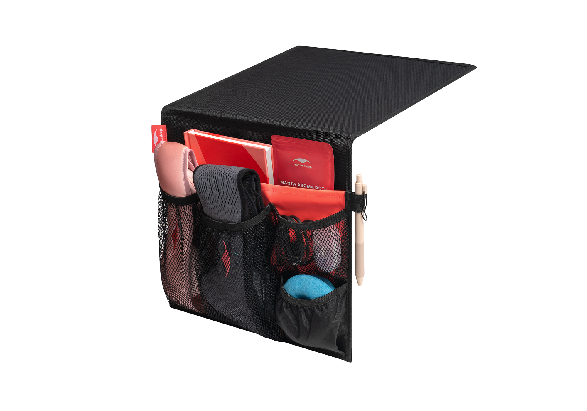Studio shot of a black and coral Manta Bedside Caddy filled with sleep masks, a notebook, and a pen, isolated on a white background.