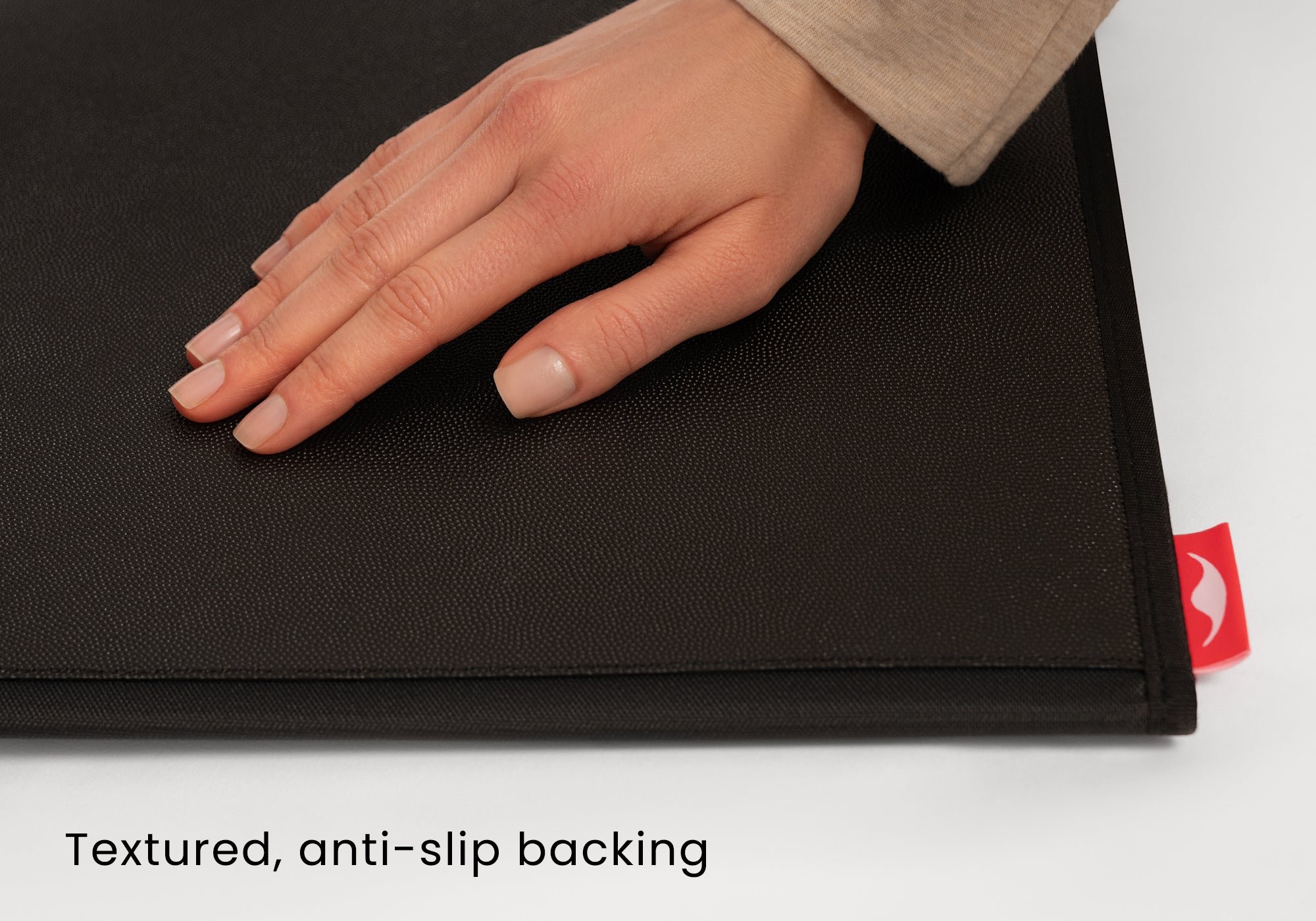 Close-up shot of a hand resting on the textured, anti-slip backing of a black caddy panel. Text overlay reads "Textured, anti-slip backing".