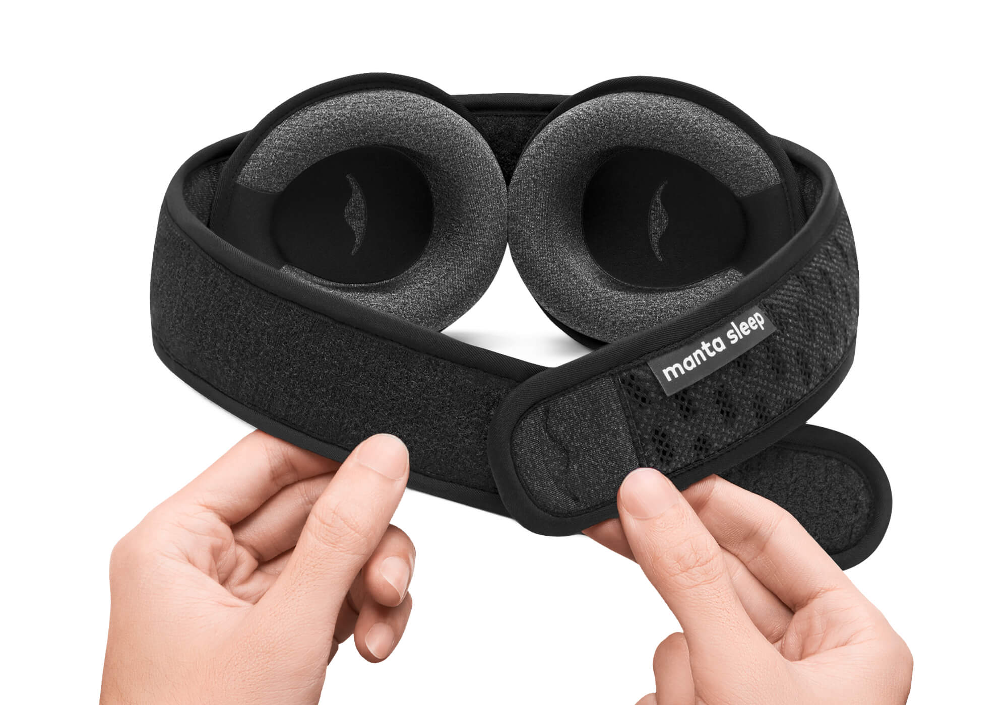 Two hands adjusting the adjustable hook-and-loop closure strap on a Carbon Black mesh Manta Sleep Mask PRO against a crisp white background.