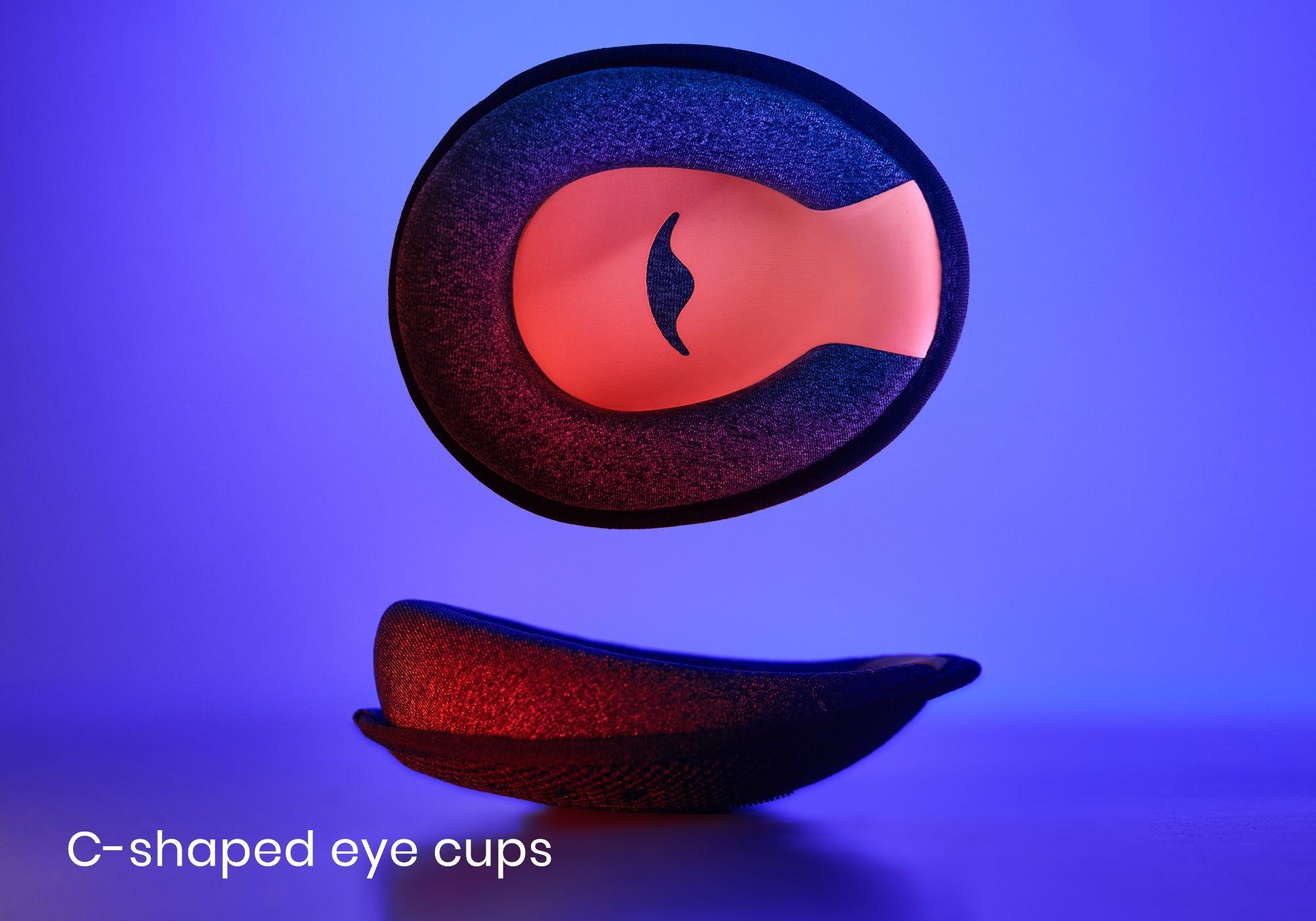 Front and side views of an ergonomic eye cup featuring a grey fabric texture and coral-colored interior with the Manta Sleep logo, under blue light, with text "C-shaped eye cups".