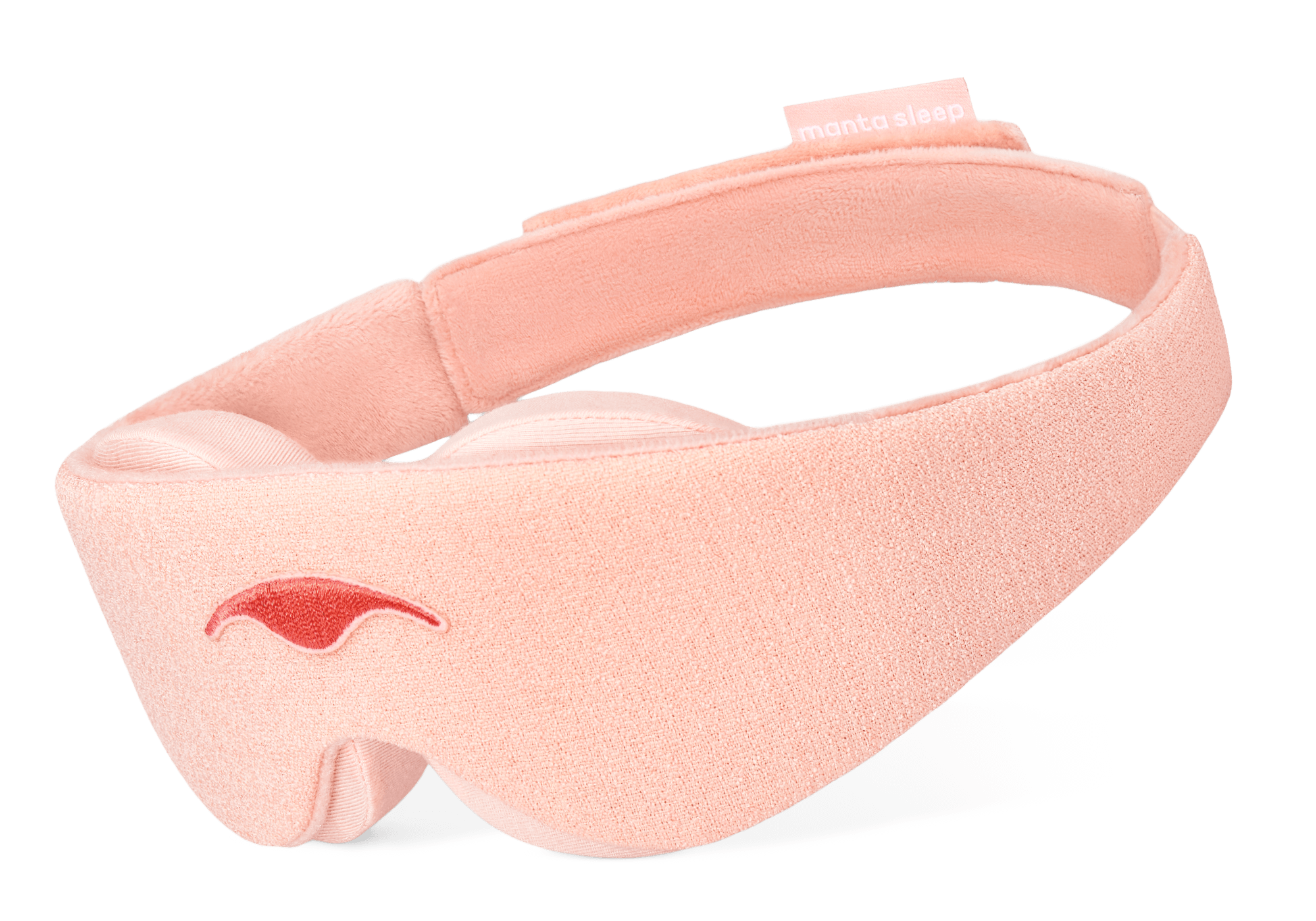 An angled product shot of the Sunrise Pink Manta Sleep Mask floating against a pure white background. The mask features a light pink soft-textured exterior, a darker pink embroidered logo on the front, thick contoured padding beneath, and a small brand tag on the upper back strap.