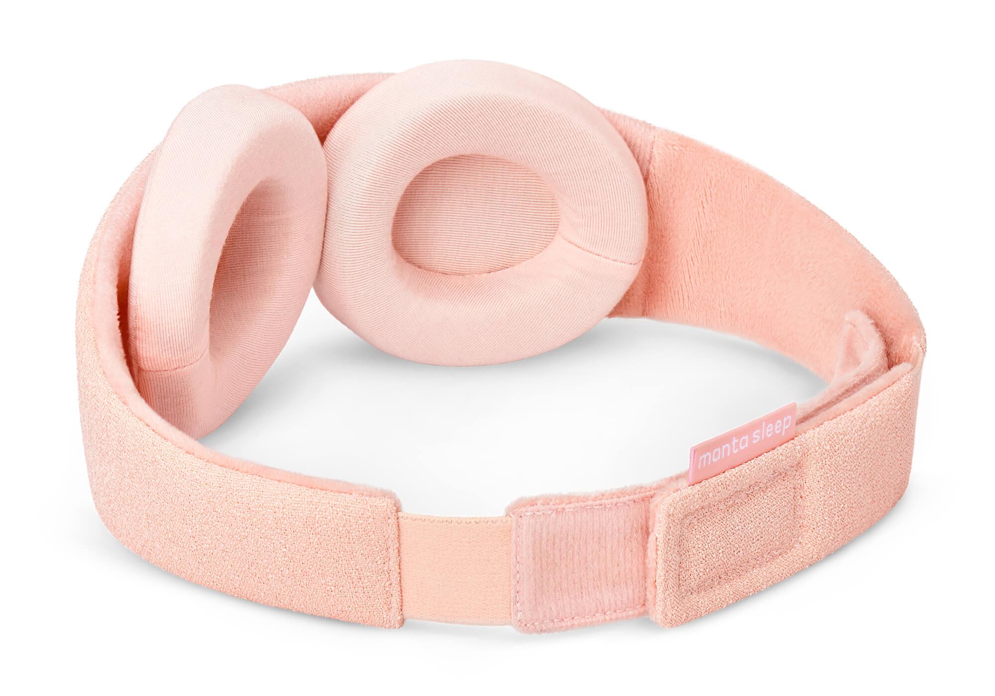 A three-quarter rear perspective of the Sunrise Pink Manta Sleep Mask isolated on a white background. This view highlights the soft, velvety pink inner lining of the strap, the adjustable hook-and-loop rear closure with a pink "manta sleep" tag, and the two detachable, thick pink eyecups.