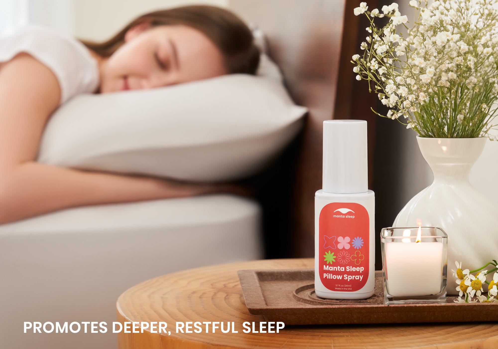 Manta Sleep Pillow Spray on a nightstand tray with a candle and flowers, with a woman sleeping in the background. Text: Promotes deeper, restful sleep.