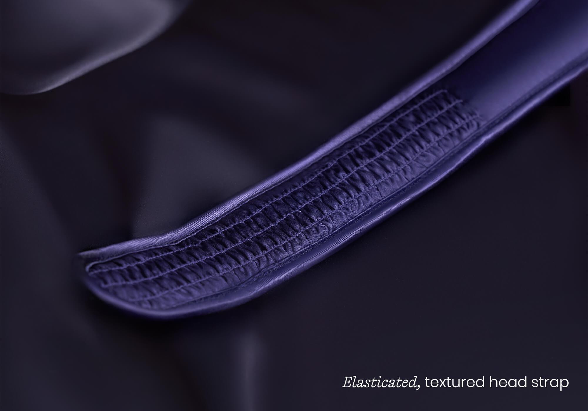 Macro close-up of a glossy, purple silk sleep mask showing detailed ruching, captioned "Elasticated, textured head strap".