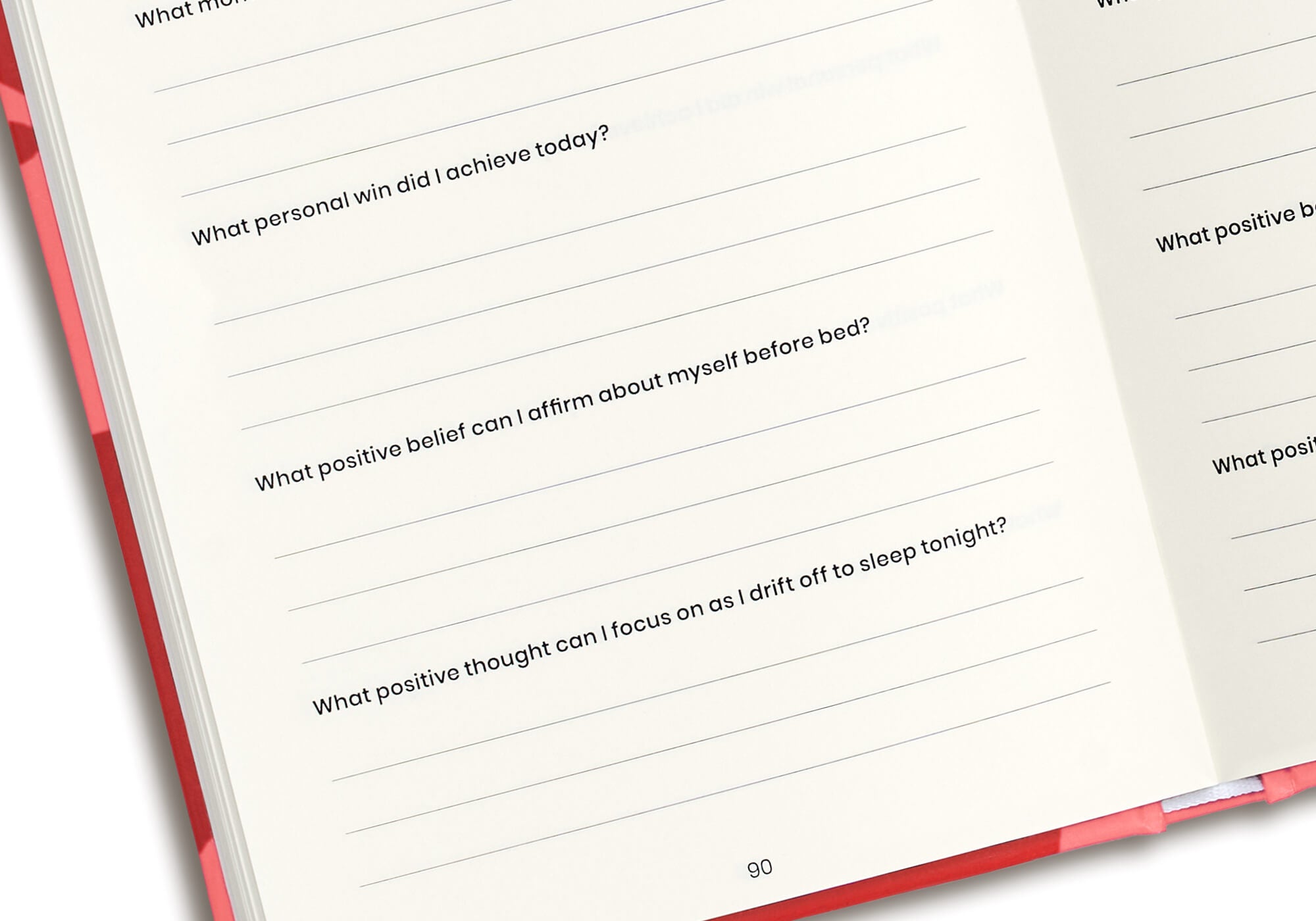 Close-up shot of the white pages inside a red journal, displaying printed reflection questions above blank writing lines.