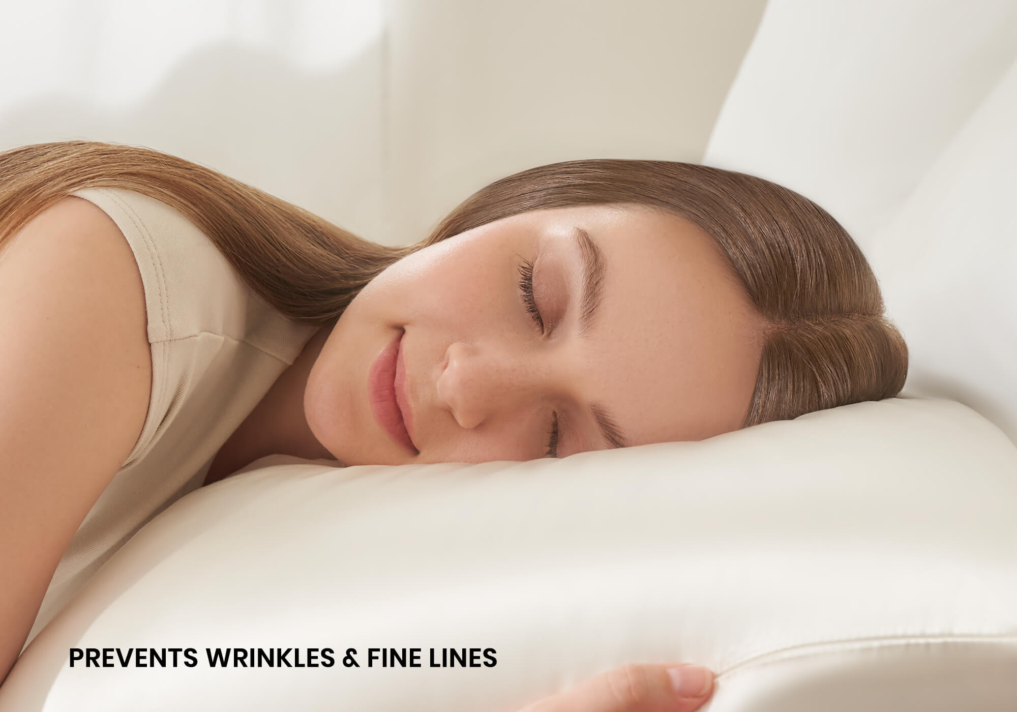 Close-up of a smiling woman sleeping on a pearl white Manta Sleep silk pillowcase with text overlay "Prevents wrinkles & fine lines".