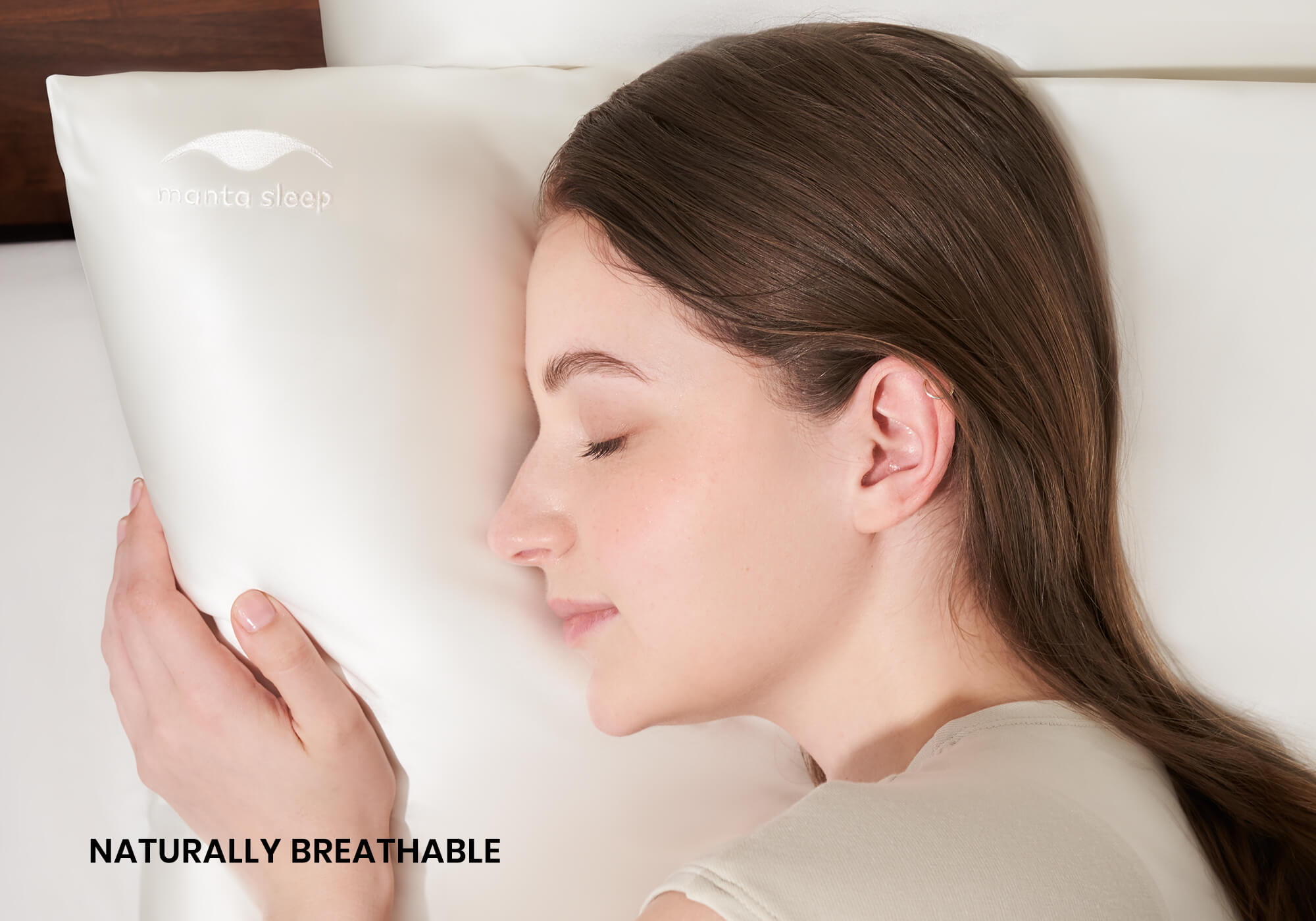 A woman sleeping peacefully on her side on a pearl white Manta Sleep silk pillowcase. Text overlay: "Naturally breathable".