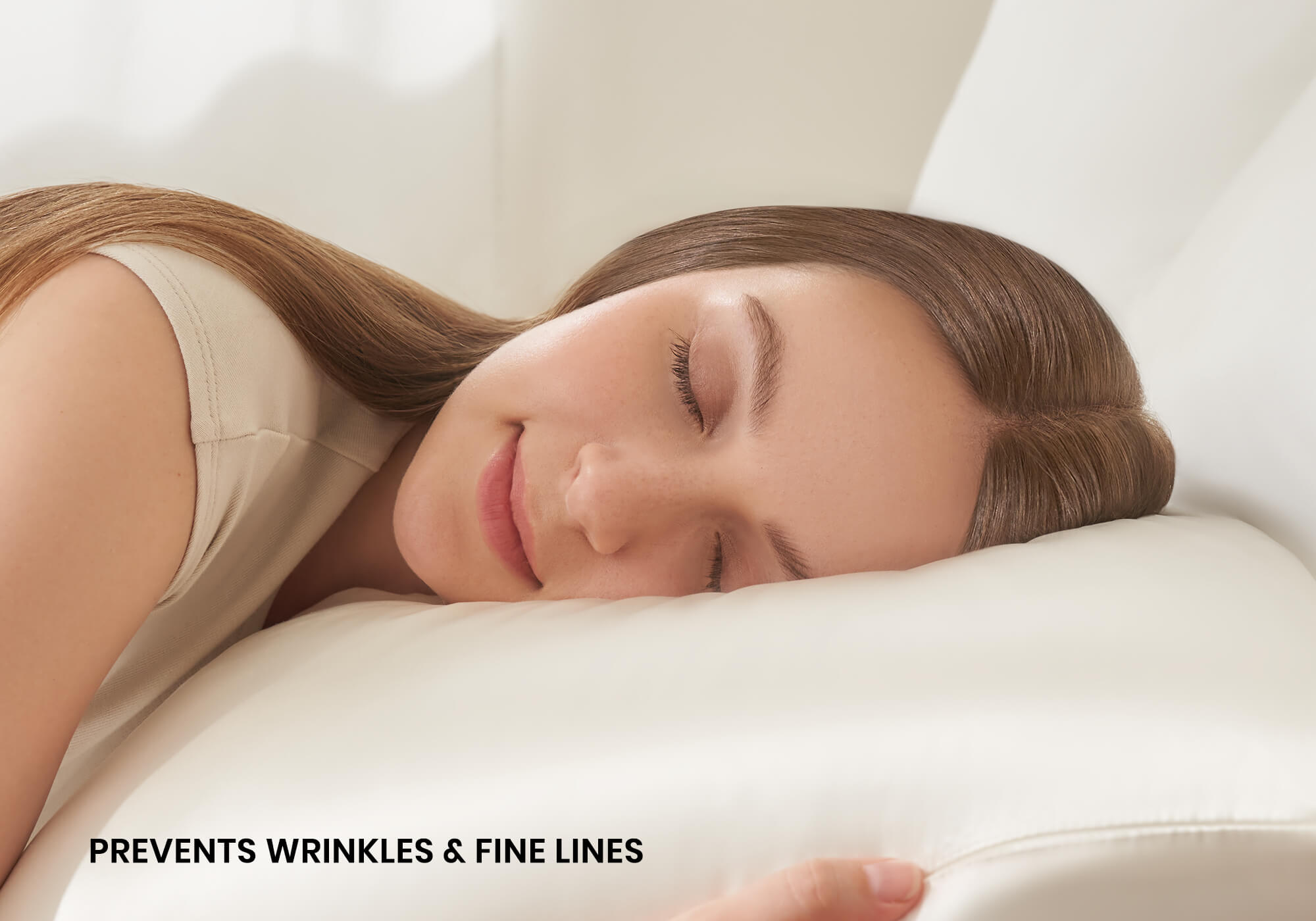 Close-up of a smiling woman sleeping on a pearl white Manta Sleep silk pillowcase with text overlay "Prevents wrinkles & fine lines".