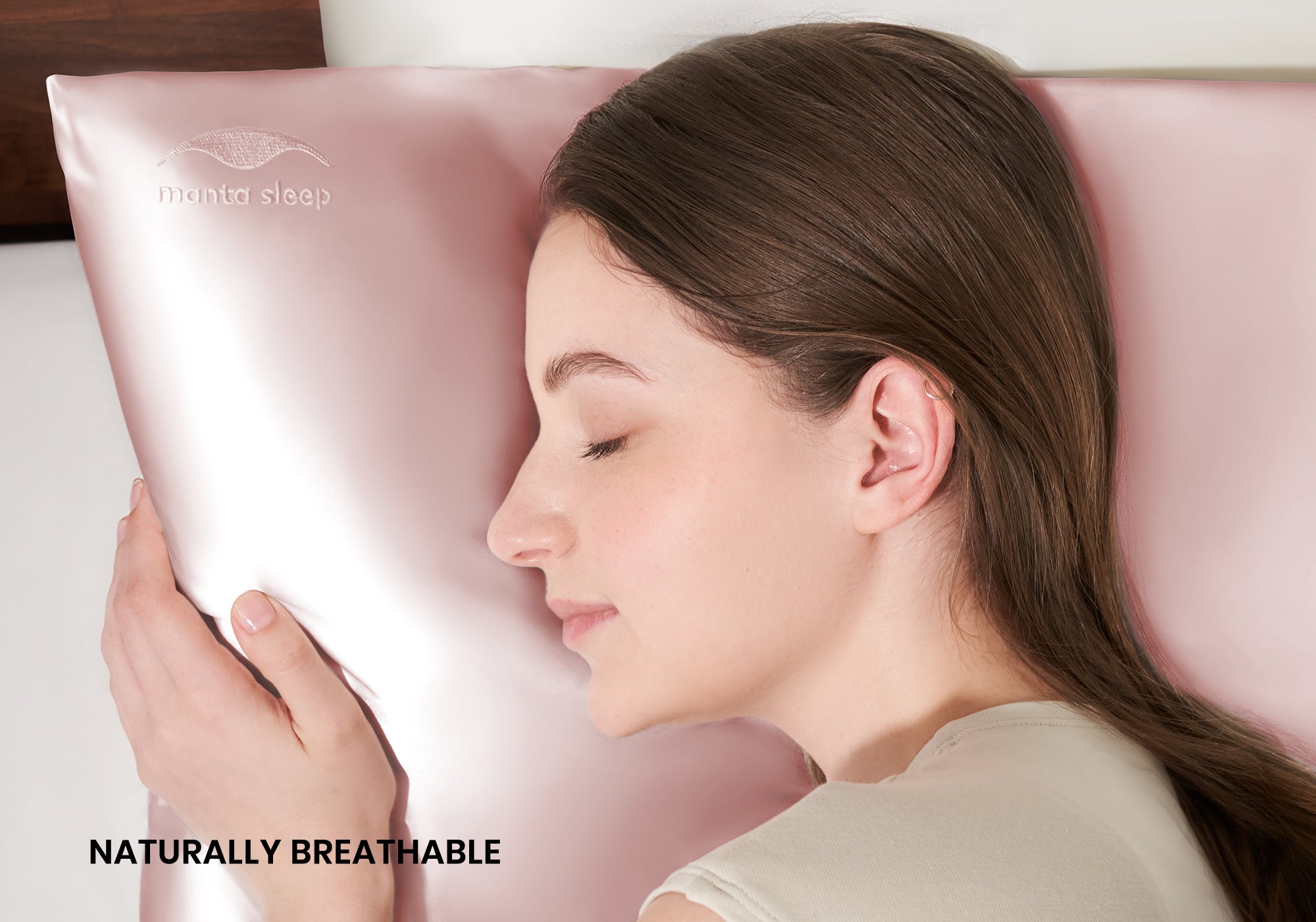 A woman sleeping peacefully on her side on a rose pink Manta Sleep silk pillowcase. Text overlay: "Naturally breathable".
