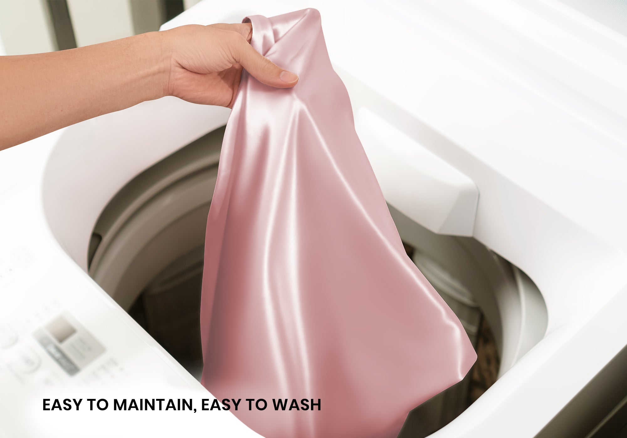 A hand lifting a rose pink silk pillowcase out of a white washing machine. Text overlay: "Easy to maintain, easy to wash".