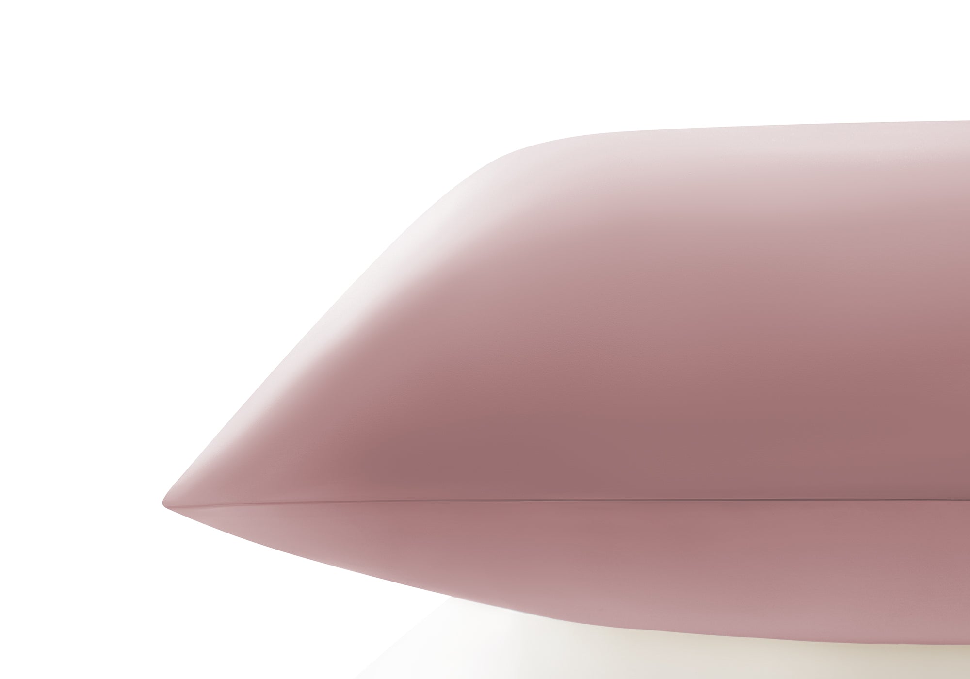 Side profile close-up showing the smooth edge and sleek texture of a rose pink Manta Sleep silk pillowcase.
