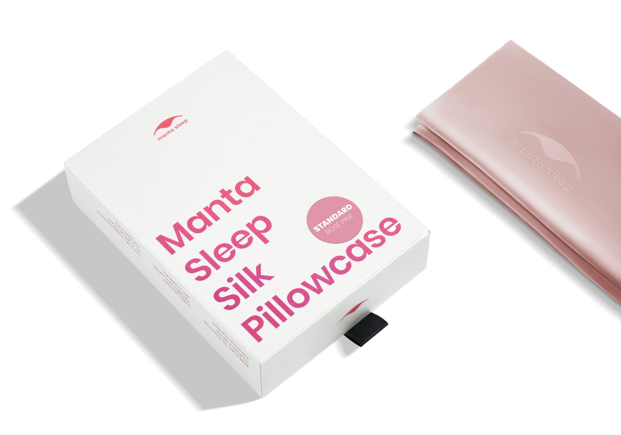 High-angle shot of the white product box with pink text and a folded rose pink Manta Sleep silk pillowcase.