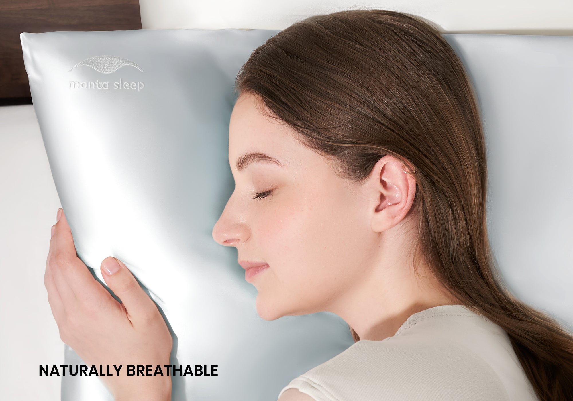 A woman sleeping peacefully on her side on a crystal silver Manta Sleep silk pillowcase. Text overlay: "Naturally breathable".