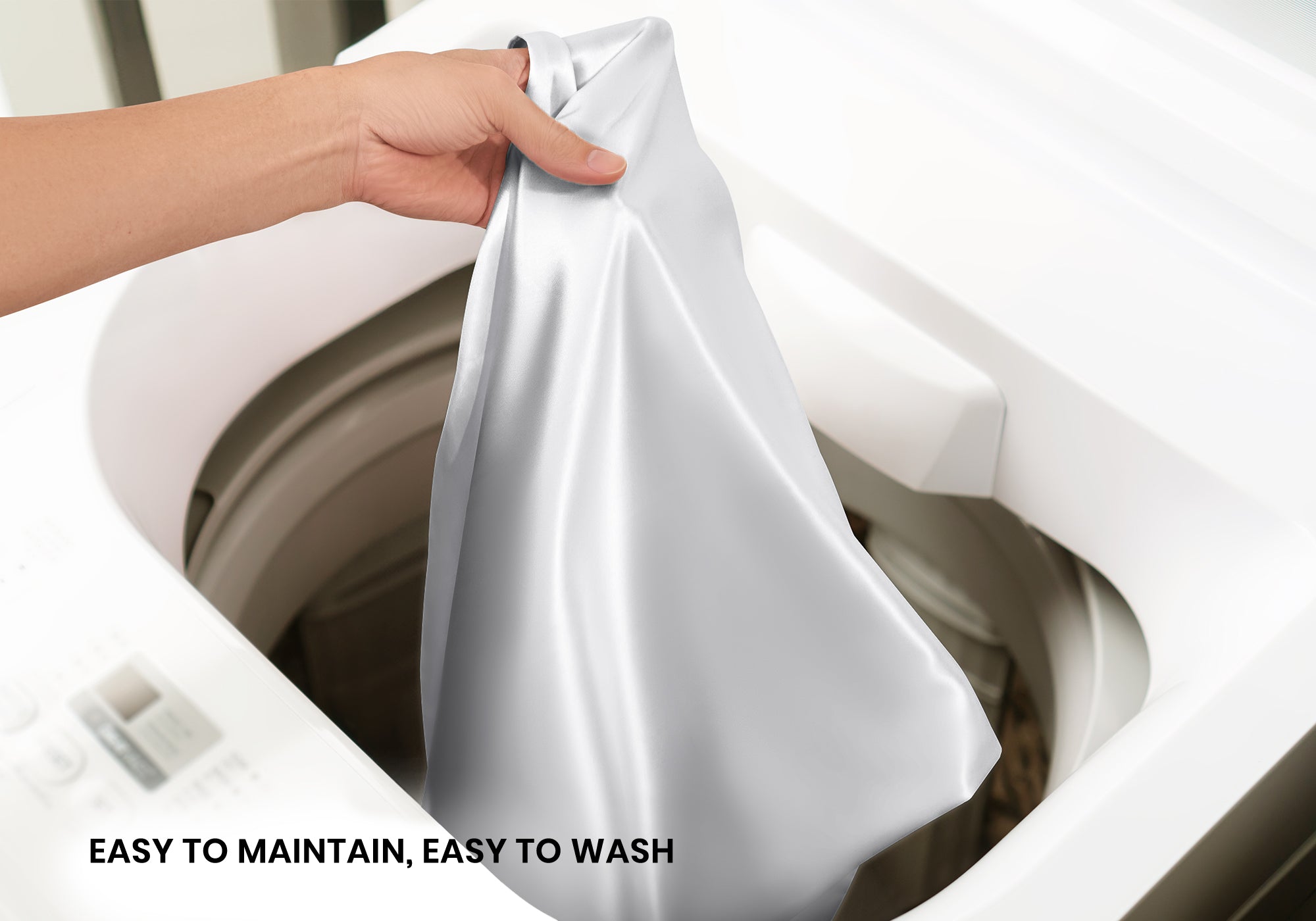 A hand lifting a crystal silver silk pillowcase out of a white washing machine. Text overlay: "Easy to maintain, easy to wash".