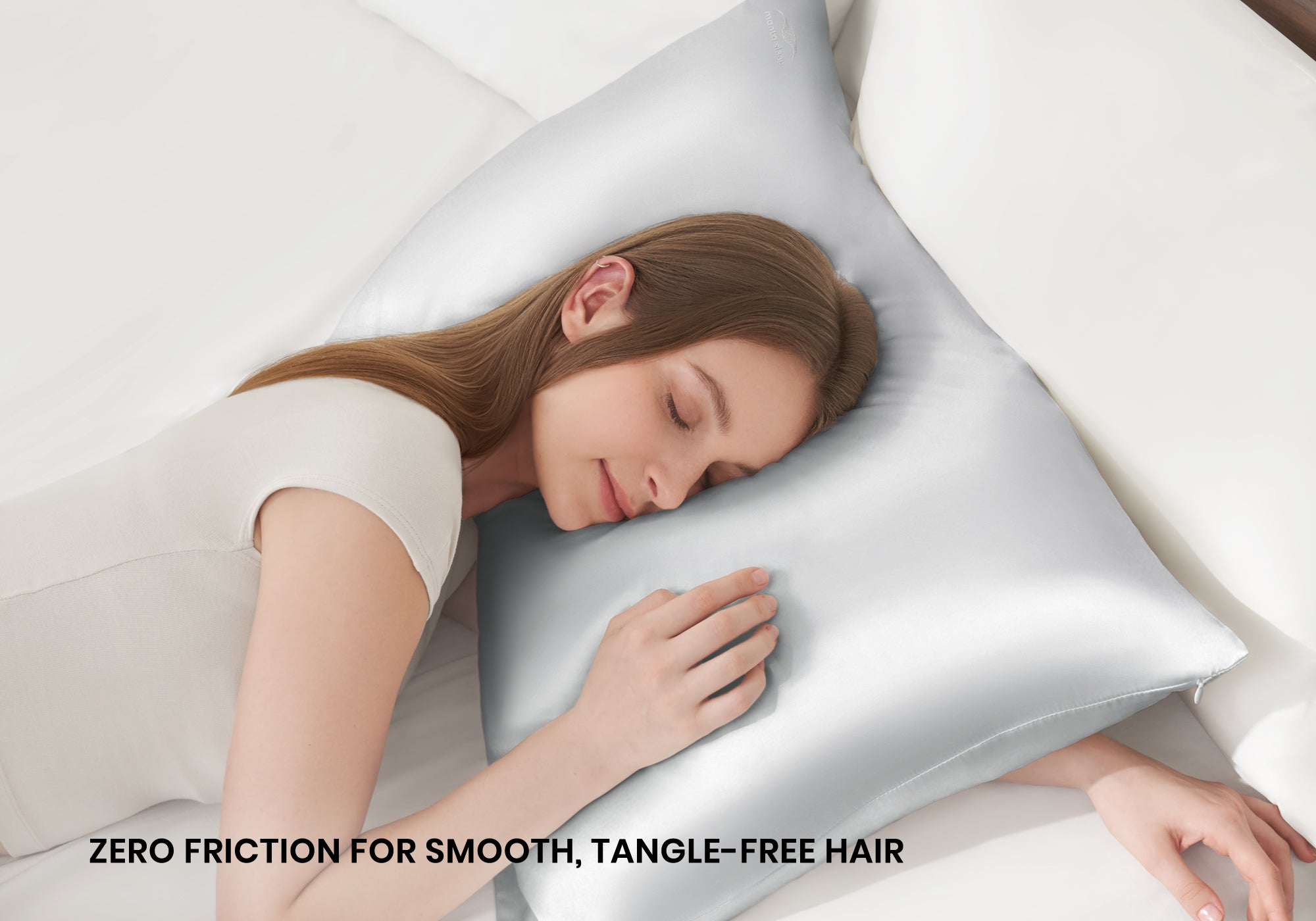 Overhead shot of a woman sleeping peacefully on a crystal silver Manta Sleep silk pillowcase with text overlay "Zero friction for smooth, tangle-free hair".