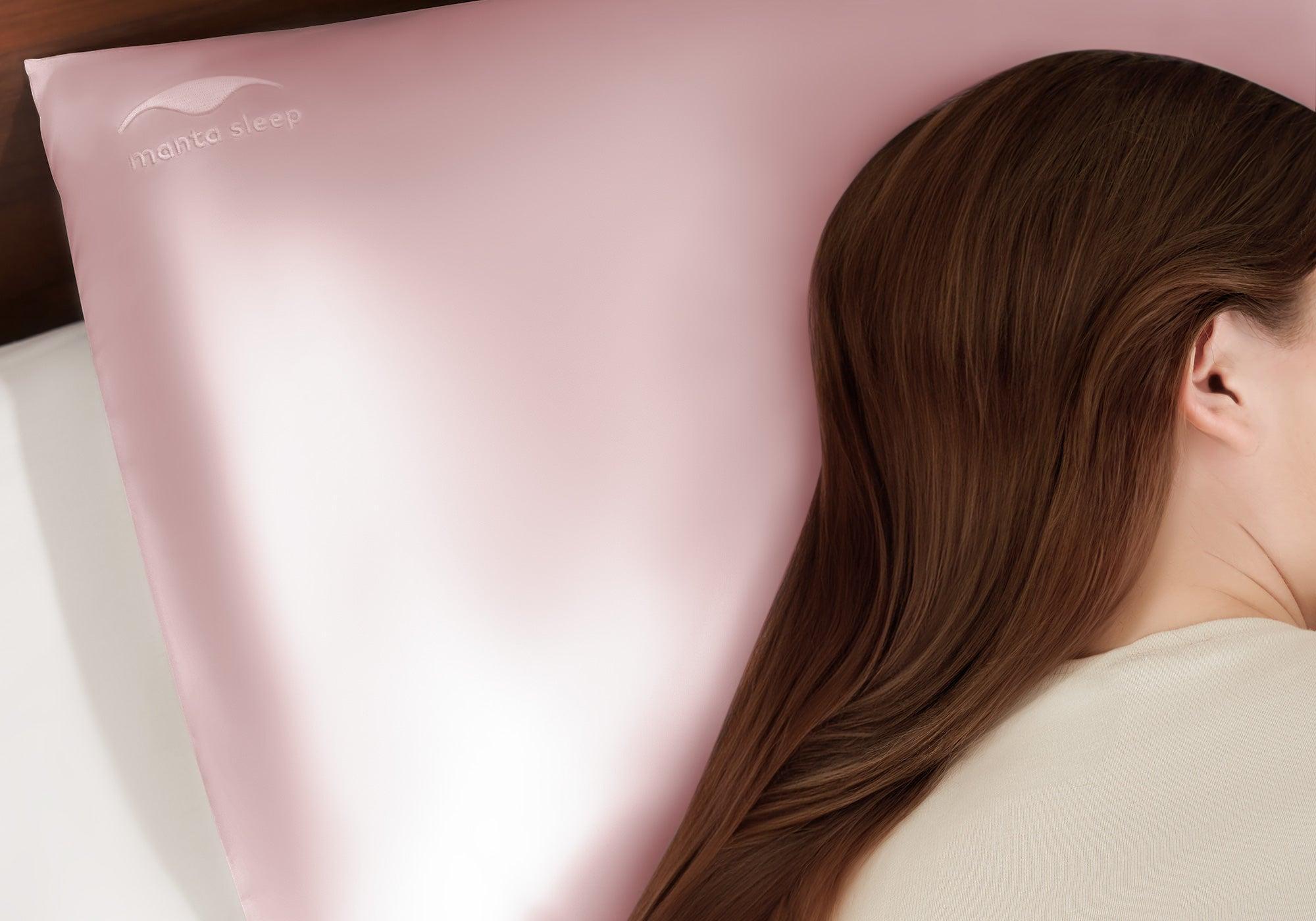 Close-up profile of a woman with long, smooth brown hair resting on a rose pink Manta Sleep silk pillowcase.