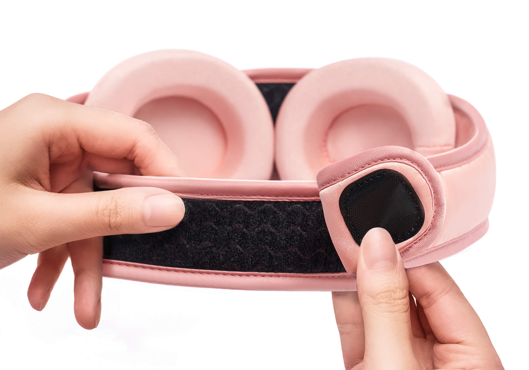 Hands demonstrating the black hook-and-loop closure on the adjustable strap of a pink Manta SILK Sleep Mask.