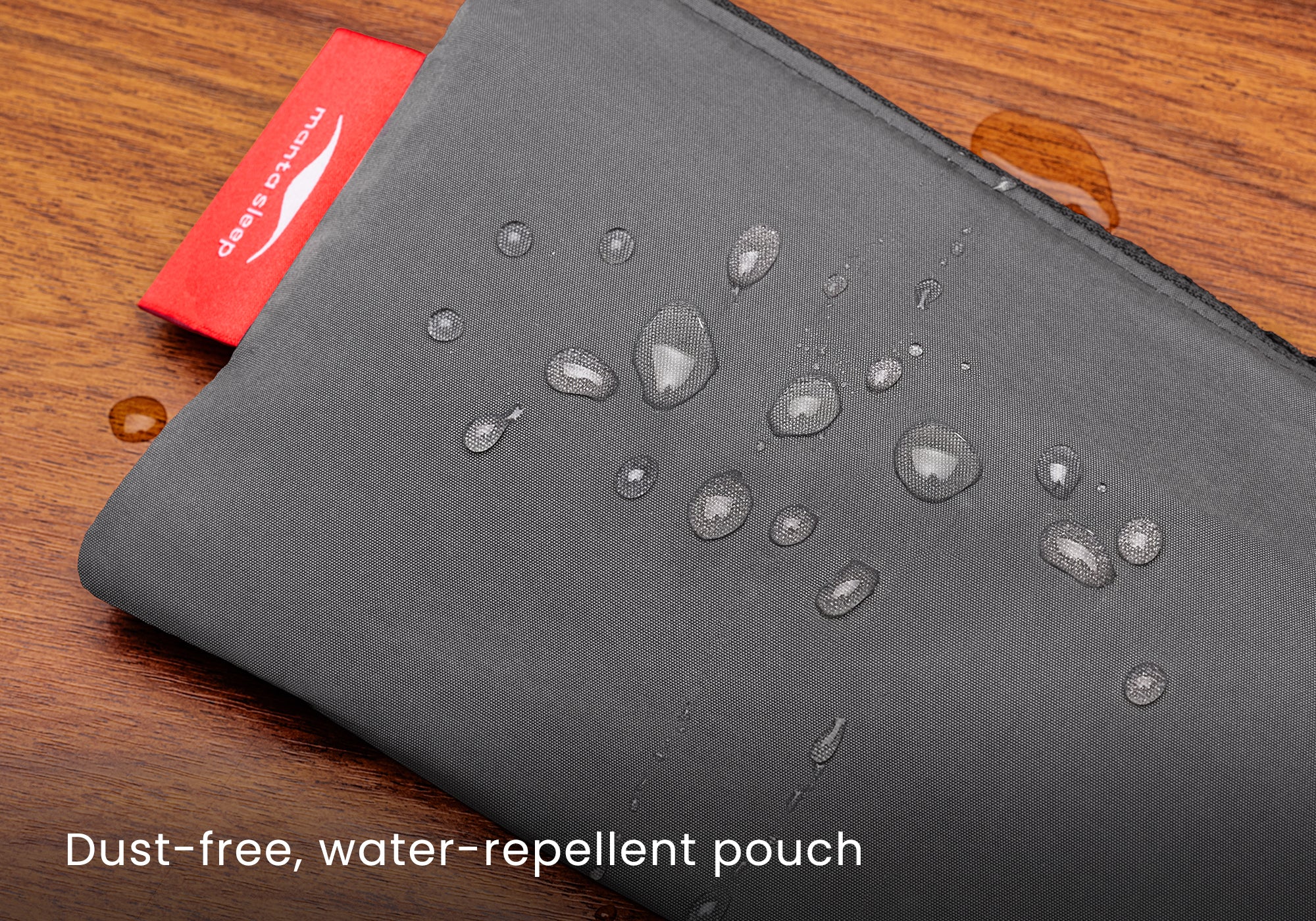 Close-up shot of water droplets rolling off the surface of the water-repellent grey pouch fabric. Text overlay: "Dust-free, water-repellent pouch".