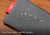 Close-up shot of water droplets rolling off the surface of the water-repellent grey pouch fabric. Text overlay: "Dust-free, water-repellent pouch".