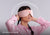 Woman wearing a pink Manta SOUND Mask over her eyes with white soundwave lines radiating around her head and text reading "Immersive sound".