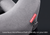 Close-up of a gray plush neck pillow with a red Manta Sleep brand tag and a suction cup base, on a dark background with text at the bottom reading 'Luxurious microfleece that's friendly on your skin'.