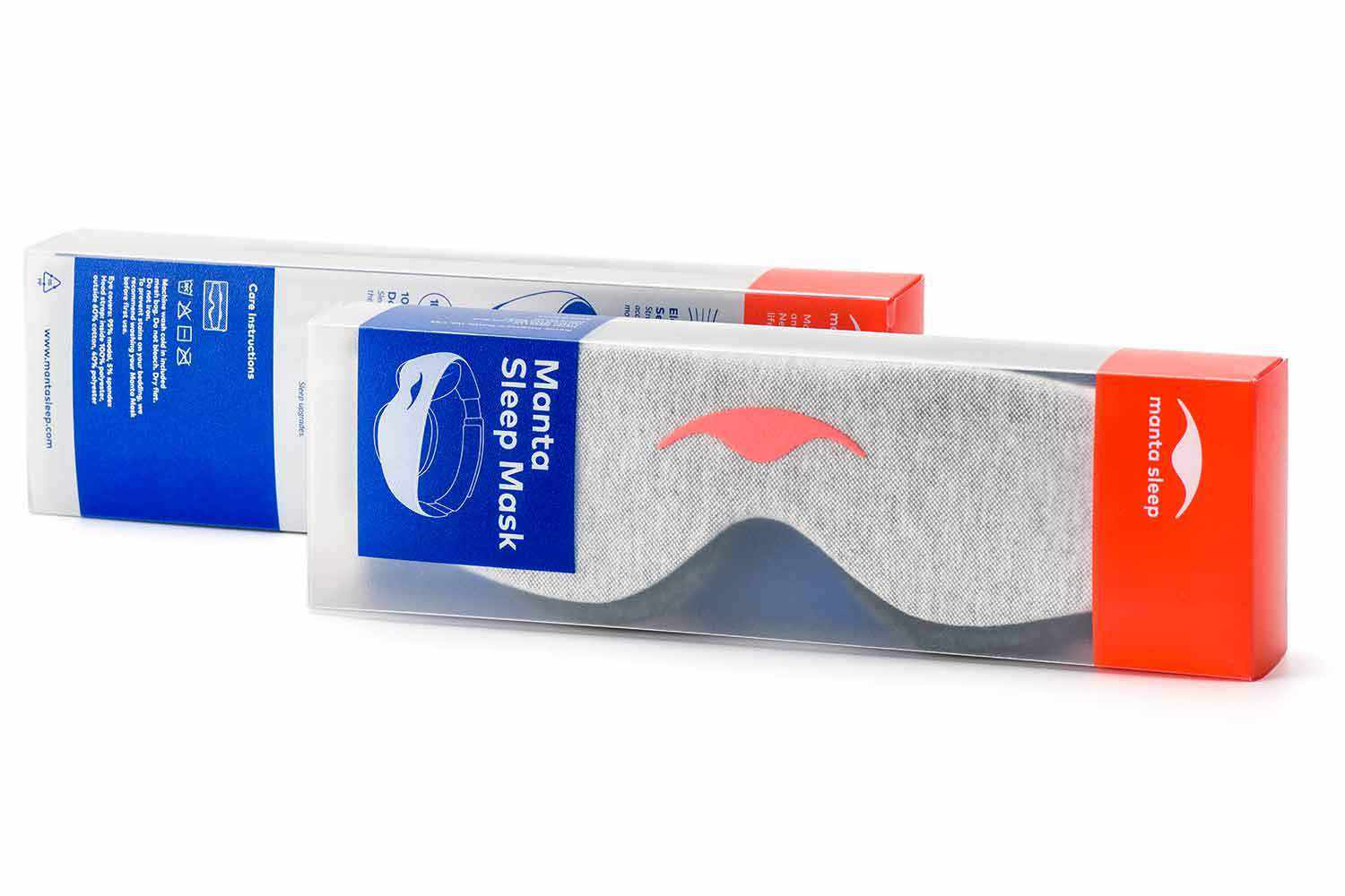 Two retail packaging boxes for the Manta Sleep Mask are displayed against a clean white background. The box in the foreground features a clear plastic window showing the light gray sleep mask with its signature coral logo inside, accented by a bright blue panel on the left reading "Manta Sleep Mask" and a vibrant coral-red panel on the right with white branding text.