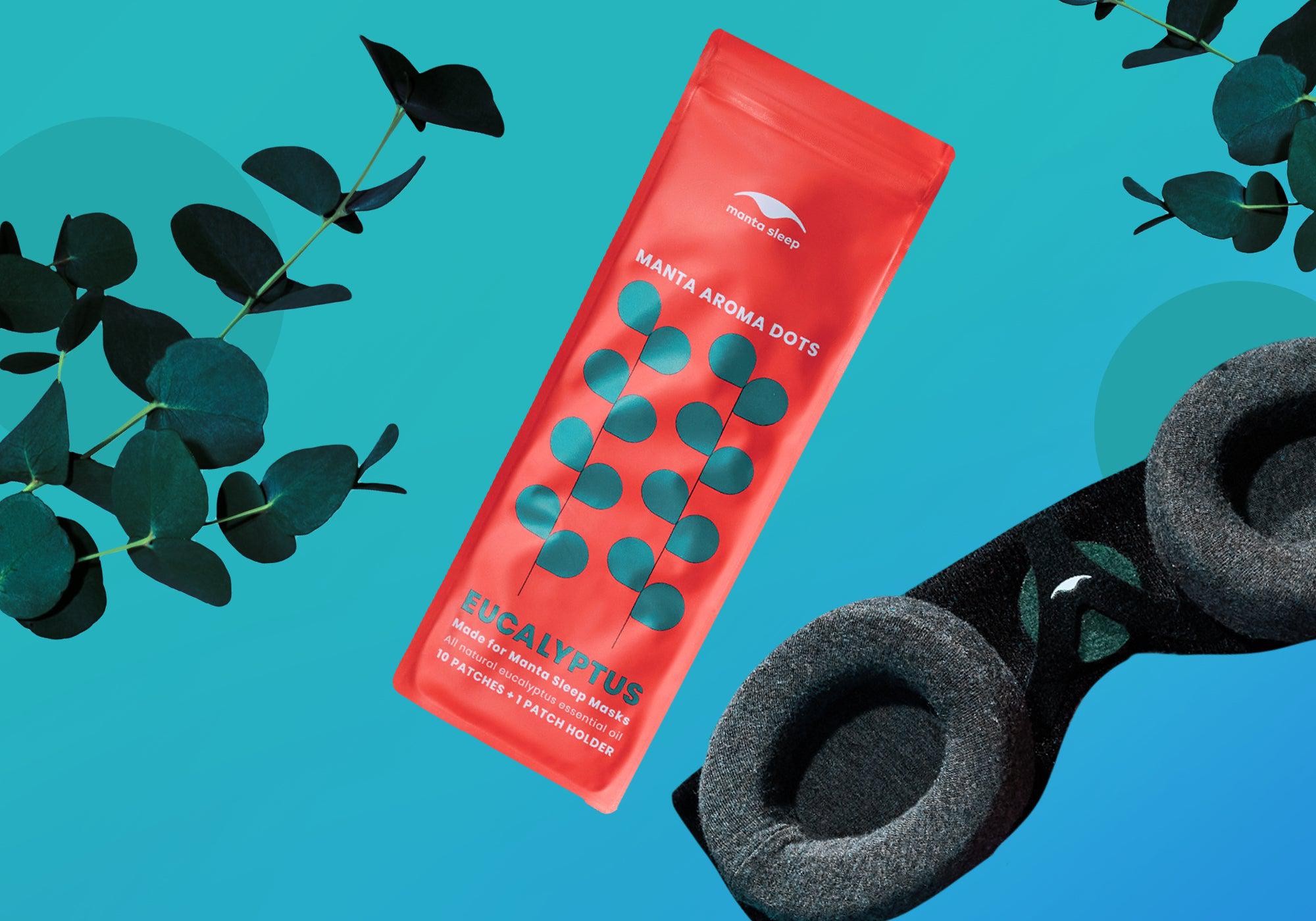Eucalyptus-scented Manta Aroma Dots packaging shown alongside fresh eucalyptus leaves and a black sleep mask, on a bright teal background.