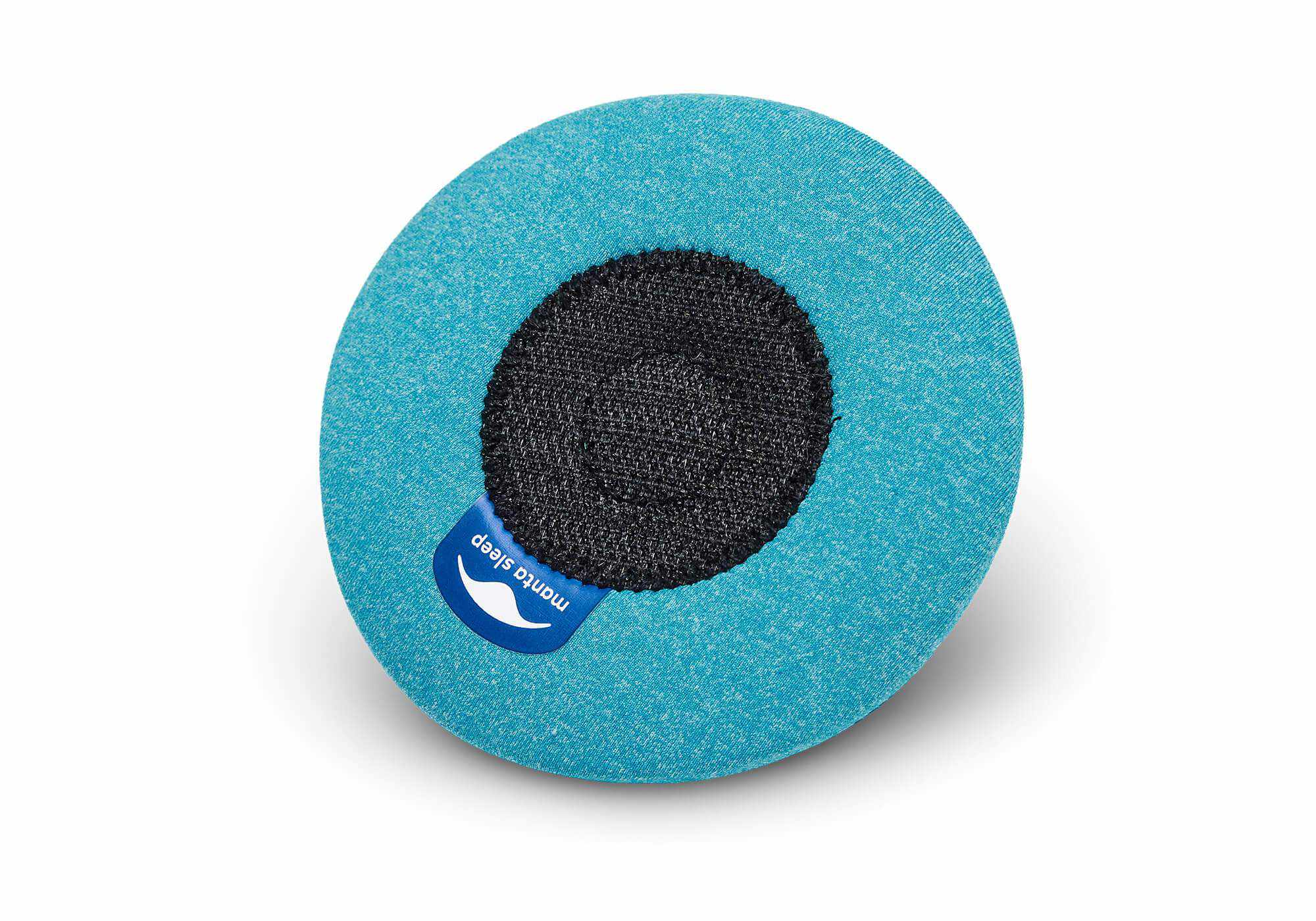 The back view of a blue-teal circular eye cup, showing a black circular hook-and-loop patch and a blue Manta Sleep label.