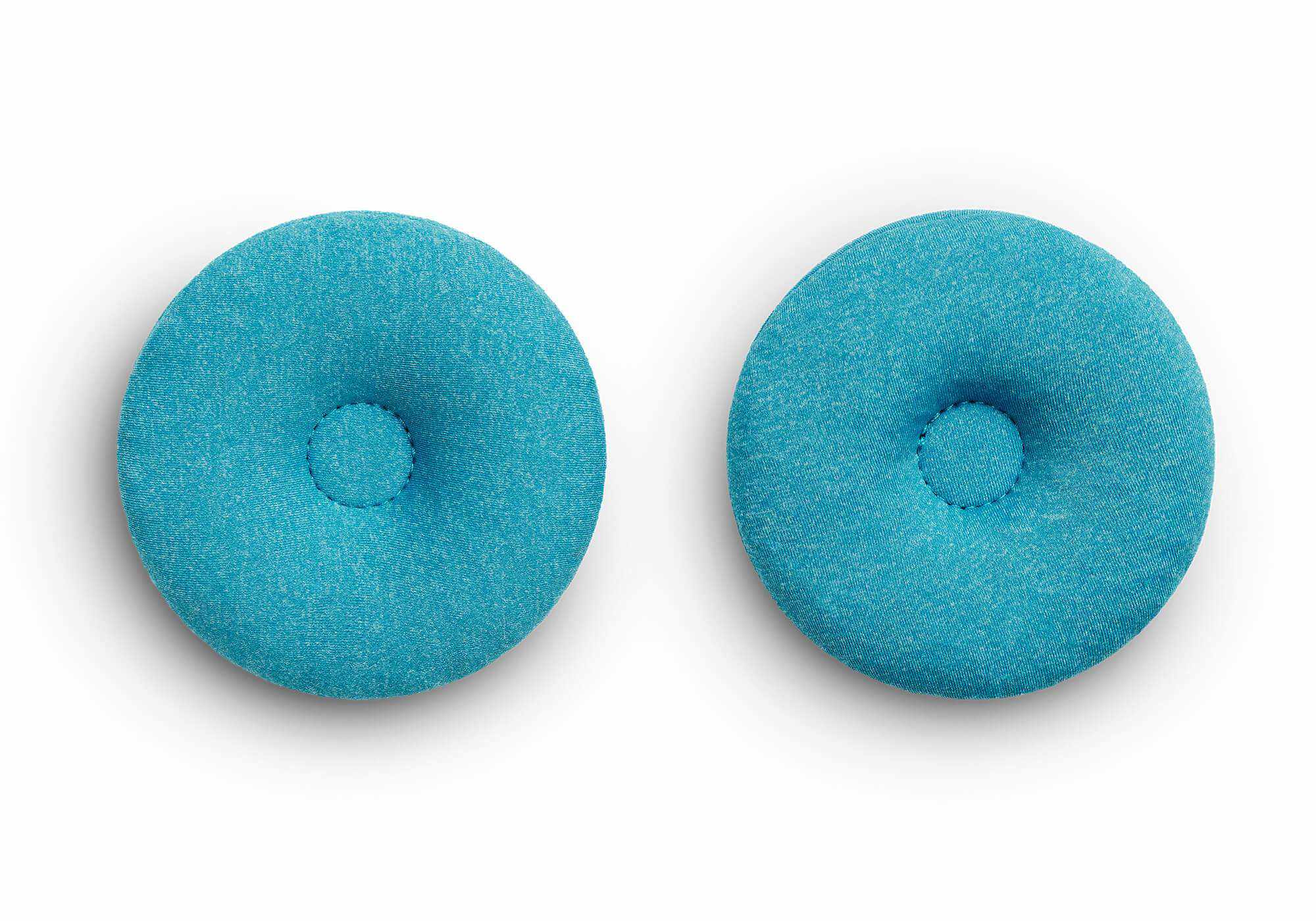 Top-down view of a pair of circular, textured blue-teal fabric eye cups with indented centers, isolated on a white background.