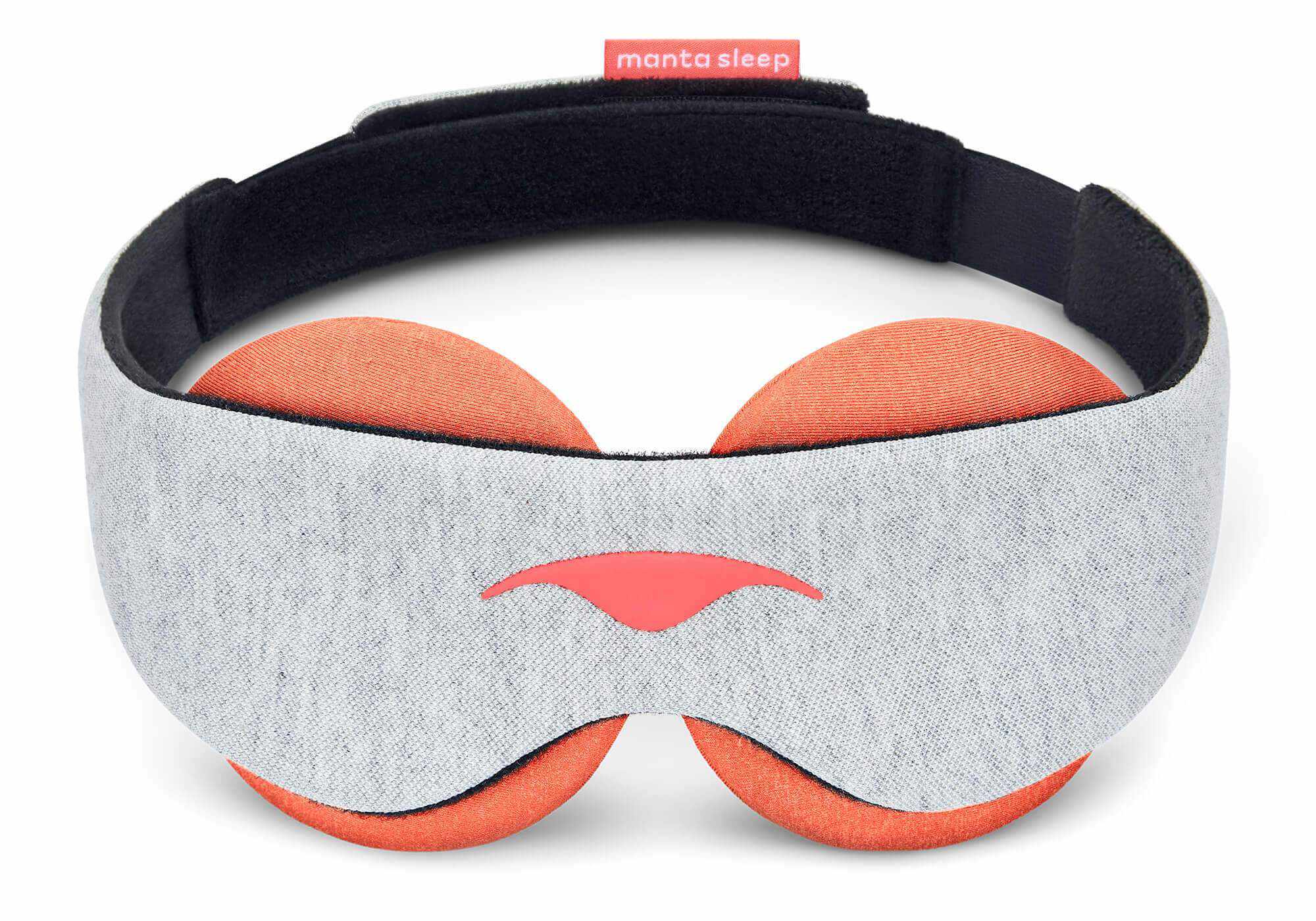 A front-facing vertical view of the Manta STEAM Sleep Mask standing upright against a white background. The mask features a wide, contoured front band made from a soft light gray heathered knit fabric with a coral-red Manta Sleep logo centered near the lower nose bridge cutout. The large, circular terracotta-orange eye cups extend symmetrically above and below the band.