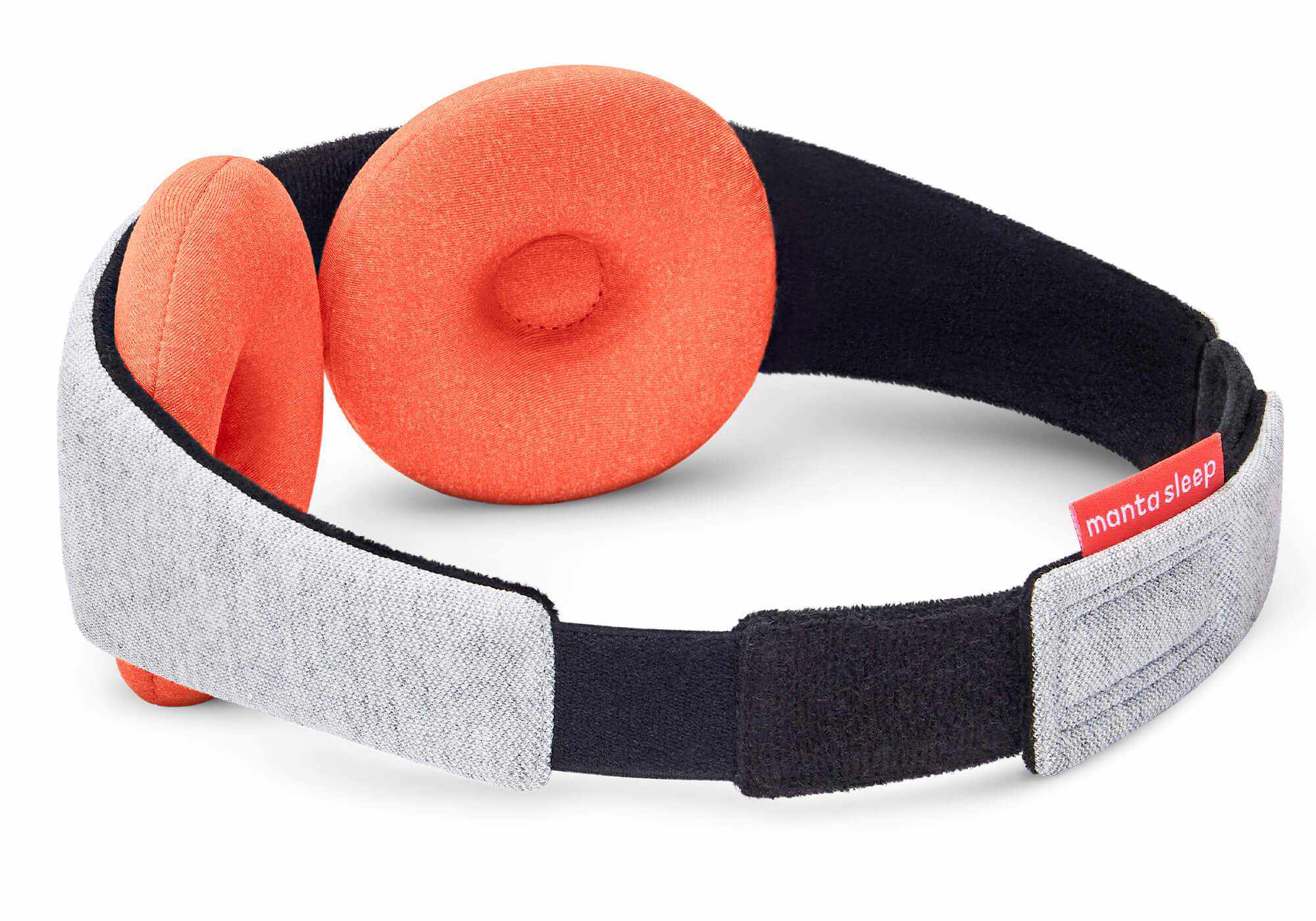 A rear-angle product shot showing the looped composition of the Manta STEAM Sleep Mask against a plain white background. The image showcases the plush black interior lining paired with two large, circular terracotta-orange eye cups, while the light gray heathered outer strap loops around to display its black fastening track and a red brand tag.
