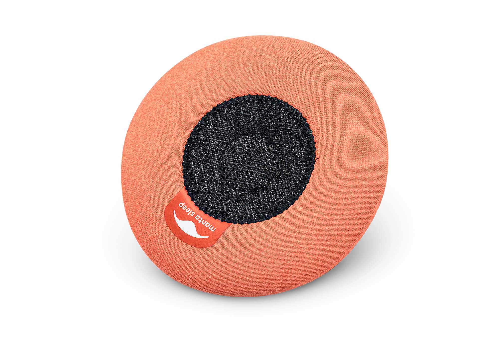 The reverse side of a circular orange eye cup, showing its black hook-and-loop fastening circle and a red Manta Sleep label.