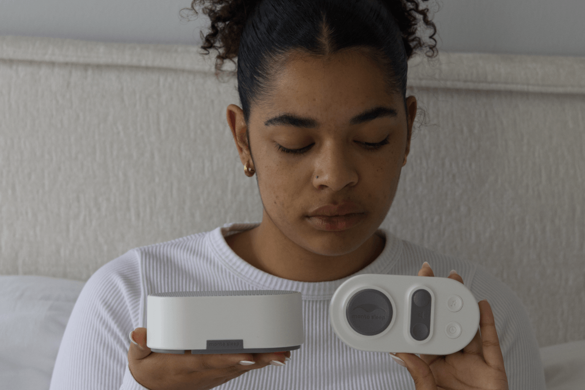 A woman holding Stone White Manta White Noise Machine and its remote pad in her hands.