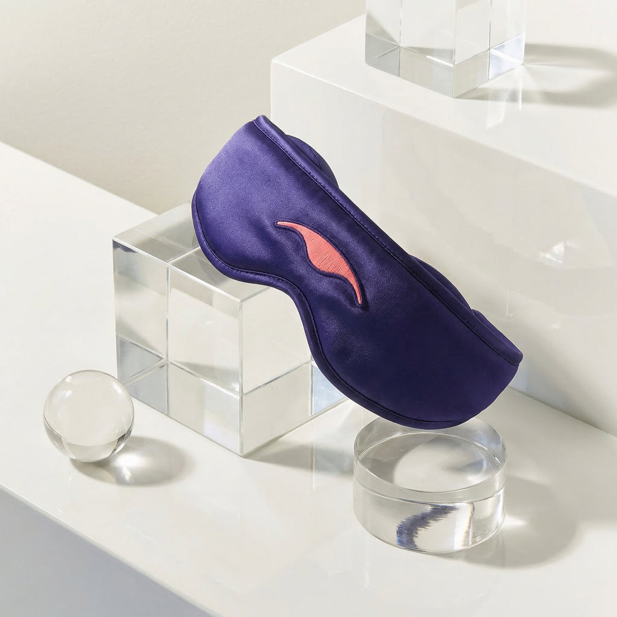 Purple Manta SILK Sleep Mask on a clear stand against a light background.