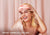 A smiling woman with pink Manta SILK Sleep Mask on her forehead, with pink curtain in the background. Text: Prevents wrinkles & fine lines.