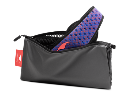 Studio shot of an open, charcoal grey zippered Manta Travel & Laundry Bag with a blue and red Manta PRO Sleep Mask peeking out, isolated on a white background.