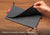 Hands unfastening the red snap buttons to unroll the grey pouch from compact travel mode into a large mesh wash bag. Text overlay: "Switch to laundry mode in seconds".