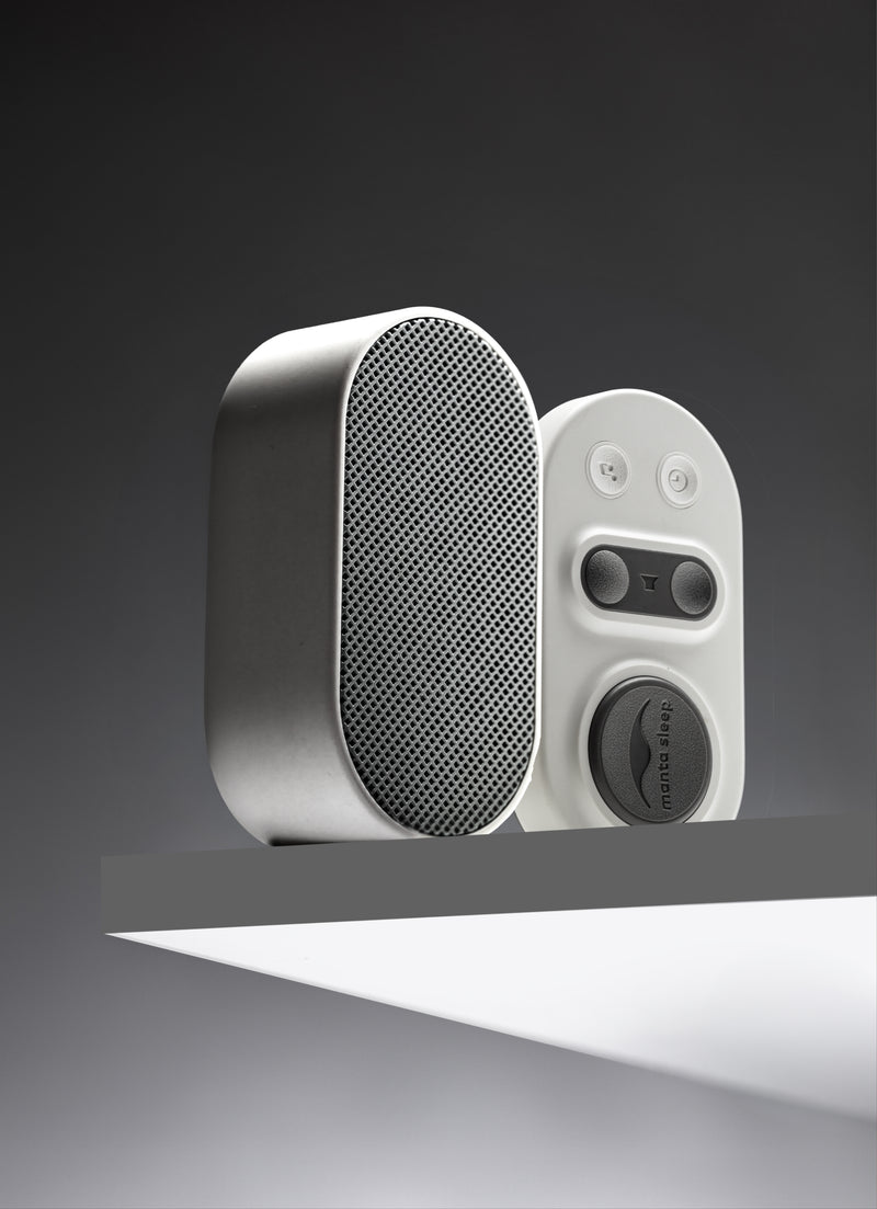 Manta White Noise Machine in Stone White color on a minimalist shelf against a dark gray background.