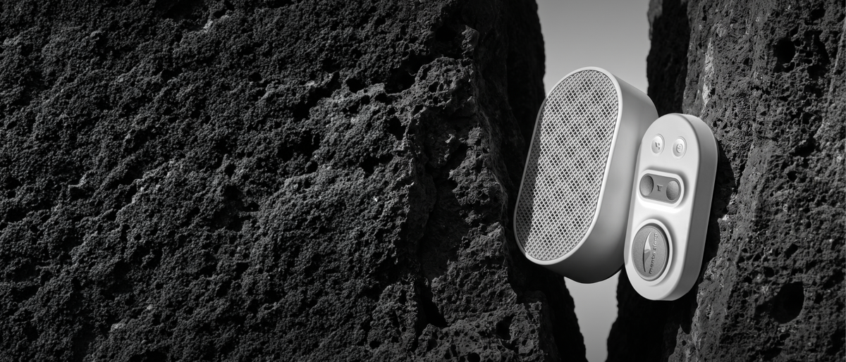 Manta White Noise Machine in Stone White color on a dark, textured rock cliffside.