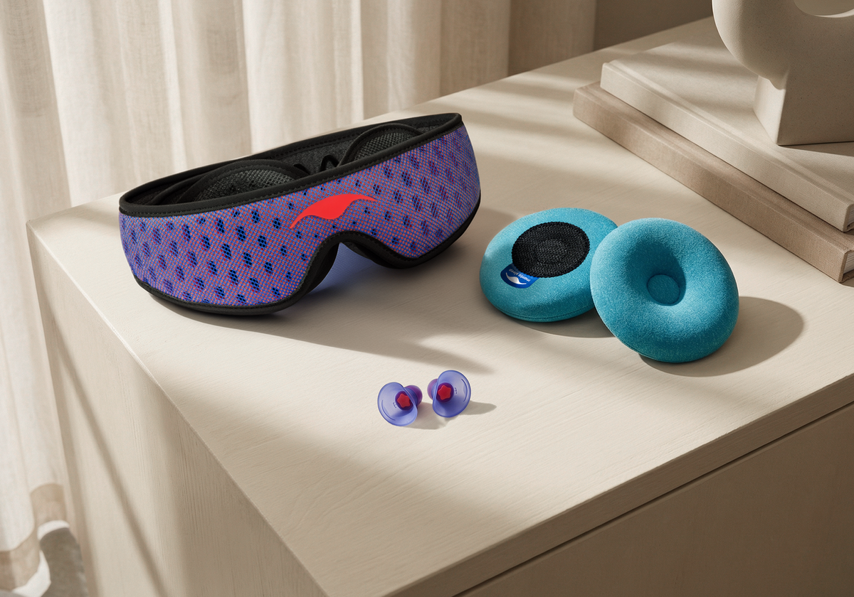 Blue and red Manta PRO Sleep Mask, blue-teal Manta COOL Eye Cups and Manta Sleep Earplugs on top of a wooden drawer.
