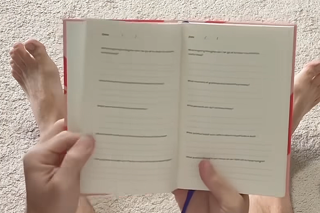 Open Manta Sleep Journal with lined pages held by hands on a textured surface.