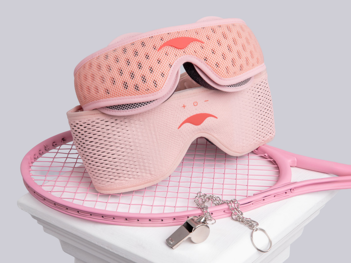 Pink Spark versions of Manta PRO Sleep Mask and Manta SOUND Sleep Mask , displayed on top of a pink tennis racket with a whistle keychain, against a light gray background.