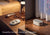 Split view of a Stone White remote and white noise machine on wooden nightstands. Text: Powerful, remote-controlled speaker.
