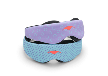 Two variants of the Manta KIDS Sleep Mask stacked on top of each other against a white background. The top mask displays a purple pattern with light blue circle outlines, while the bottom mask features a light blue pattern with dark blue wavy lines. Both masks are finished with a central orange Manta Sleep logo.