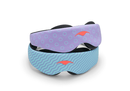 Two variants of the Manta KIDS Sleep Mask stacked on top of each other against a white background. The top mask displays a purple pattern with light blue circle outlines, while the bottom mask features a light blue pattern with dark blue wavy lines. Both masks are finished with a central orange Manta Sleep logo.